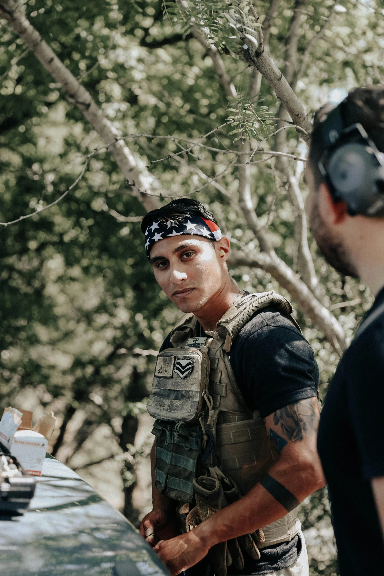 a couple of men standing next to each other, wearing tactical gear, wearing a headband, on location, asher duran