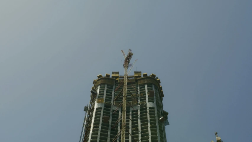 a tall building with a crane on top of it, a creature 5 meters tall, sitting down, on top of it, full building