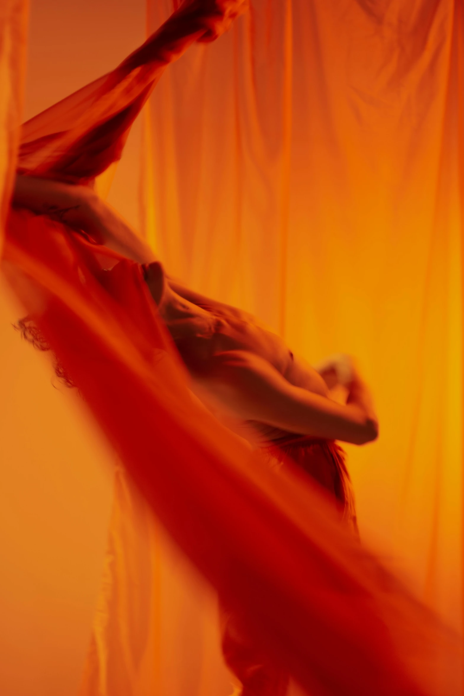 a woman that is standing in front of a curtain, an album cover, unsplash, arabesque, ryan mcginley, swirling red-colored silk fabric, orange light, showstudio