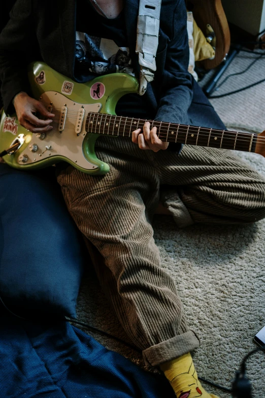 a person sitting on the floor with a guitar, pexels contest winner, photorealism, green tones, corduroy, rocking out, colored