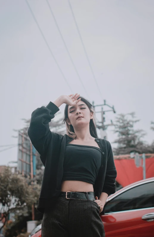 a woman standing in front of a red car, a black and white photo, inspired by Elsa Bleda, trending on pexels, realism, black hoodie, wearing crop top, thinking pose, high forehead