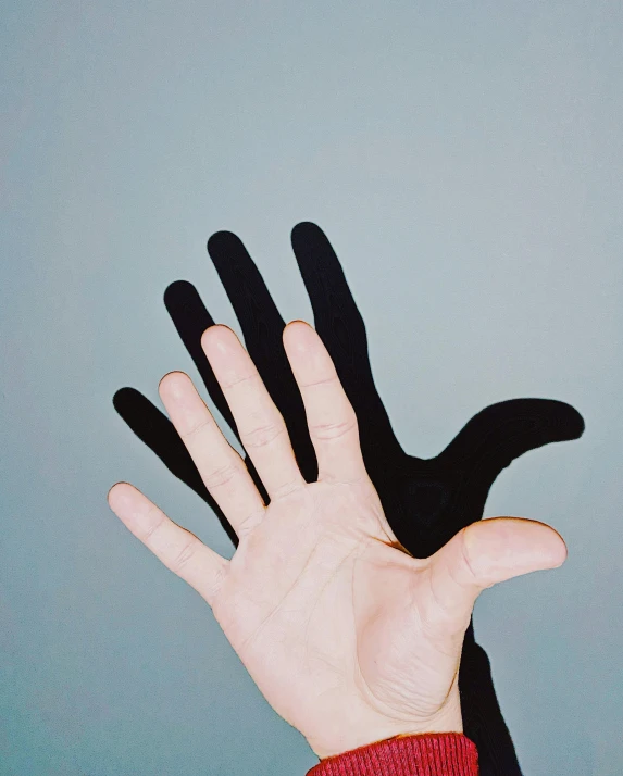 a person holding their hand up in the air, an album cover, trending on pexels, antipodeans, black paint, synthetic bio skin, holding each other, half and half