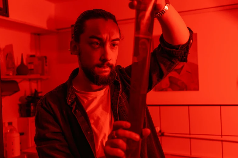 a man holding a pair of scissors in a kitchen, an album cover, pexels contest winner, serial art, red light saber, hasan piker, dynamic movie still, high red lights