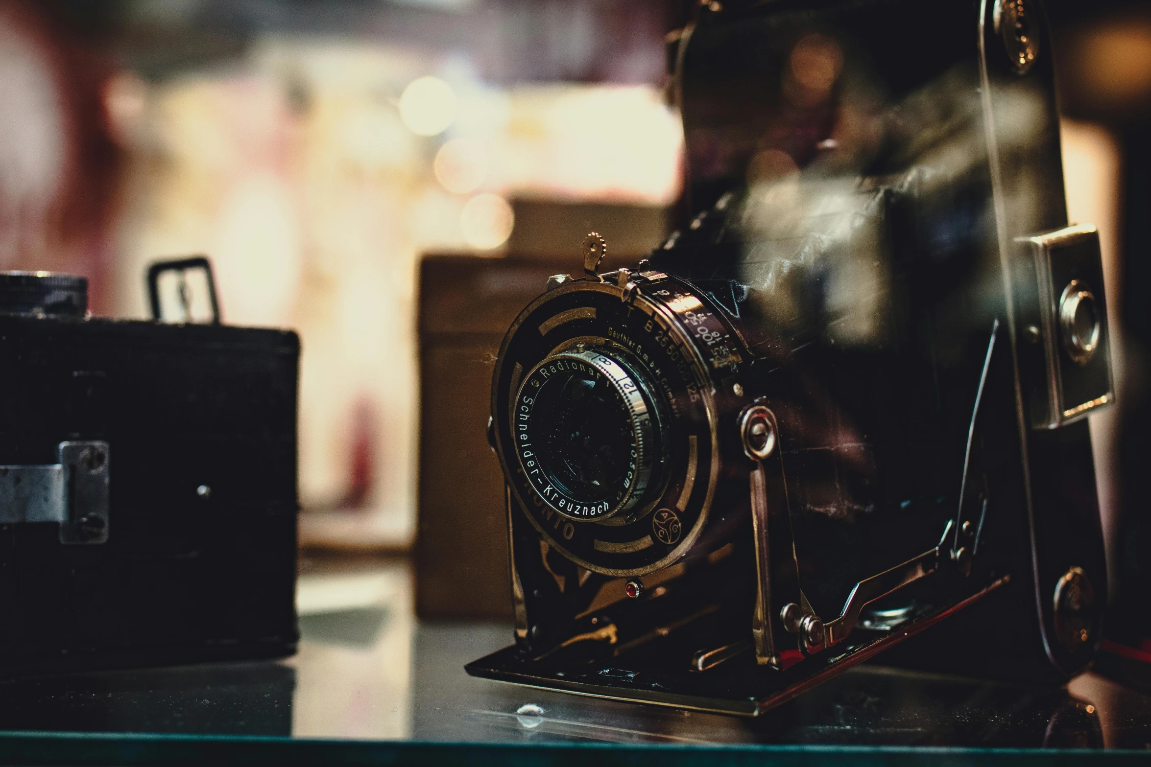 an old camera sitting on top of a glass table, pexels contest winner, a steampunk store, thumbnail, medium head to shoulder shot, old color photograph