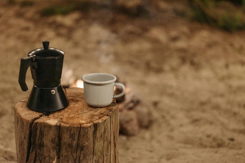 a coffee pot sitting on top of a tree stump, a still life, unsplash, glamping, braziers, close - up photo, small