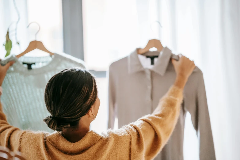 a woman looking at a dress on a hanger, trending on pexels, wearing a linen shirt, thumbnail, back towards camera, presenting wares