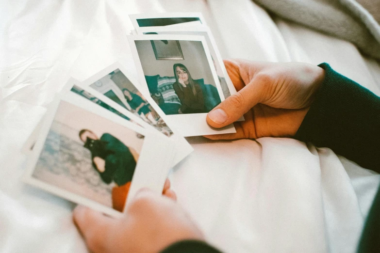 a person holding four polaroids in their hands, a polaroid photo, inspired by Elsa Bleda, trending on pexels, couple on bed, soft memories, ancient photograph, half image