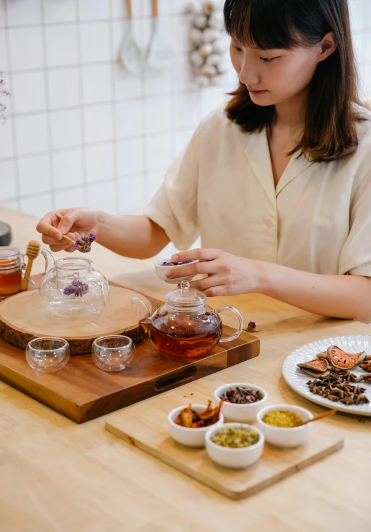 a woman that is sitting at a table with some food, a still life, inspired by Cui Bai, trending on pexels, teapots, on a wooden tray, lawther sit at table playing dnd, product introduction photo