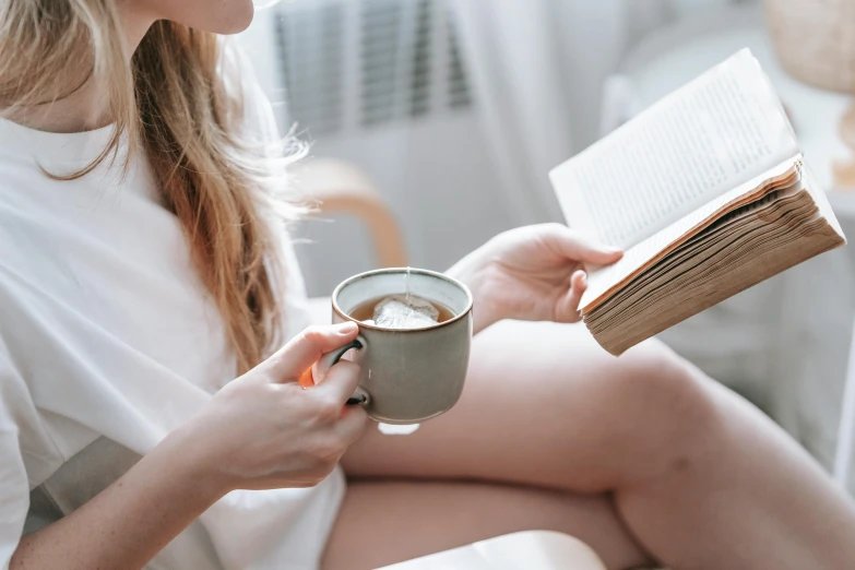 a woman reading a book and drinking a cup of coffee, by Nicolette Macnamara, trending on pexels, without makeup, mid body, dainty figure, then another