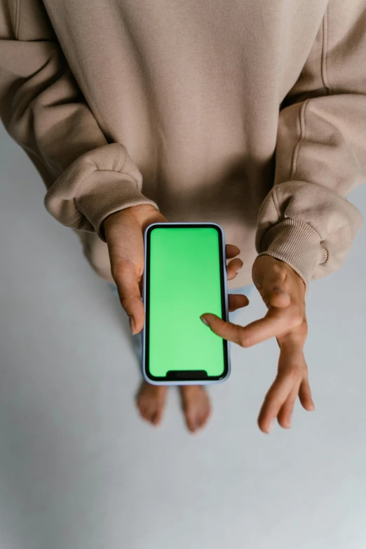 a person holding a phone with a green screen, a hologram, trending on pexels, hypermodernism, on grey background, rounded corners, no - text no - logo, 2070