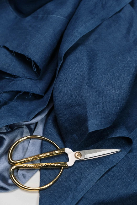 a pair of scissors sitting on top of a piece of cloth, inspired by Augustus John, baroque, midnight blue, large draped cloth, product introduction photo, fineline detail