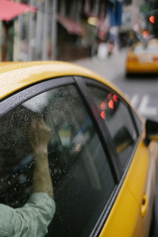 a woman taking a picture of a taxi in the rain, by Michael Goldberg, unsplash, yellow windows and details, square, sports photo, thumbnail