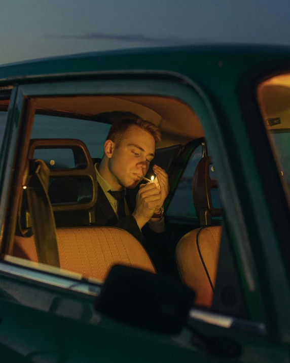 a man sitting in the passenger seat of a green car, inspired by Nan Goldin, pexels contest winner, holding a small vape, profile image, daniel clowes, smelling good