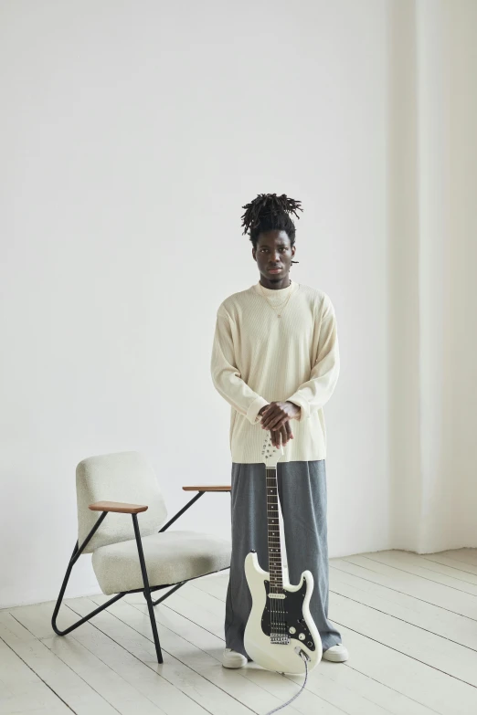 a person standing in a room with a guitar, inspired by Kamisaka Sekka, visual art, wearing a white sweater, adut akech, mid length portrait photograph, beige