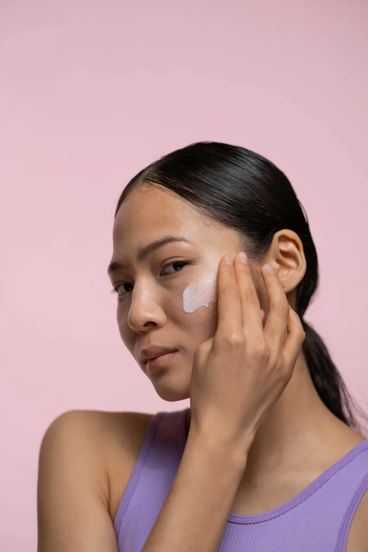 a woman putting cream on her face, trending on pexels, gemma chan, light tan, pastel', detailed product image