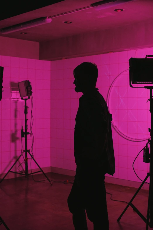 a man that is standing in front of a camera, flickr, video art, pink lighting, studio kyoto, siluettes, on location