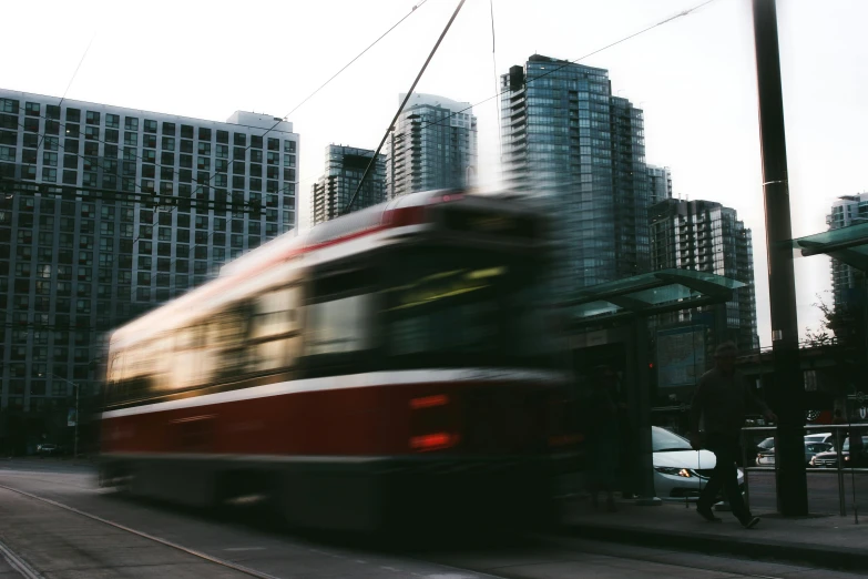 a red and white train traveling past tall buildings, pexels contest winner, happening, toronto, tram, blurry footage, stacked image