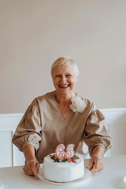 a woman sitting at a table with a cake, by Ellen Gallagher, pexels contest winner, with short bobbed white hair, celebrating a birthday, alexa65, standing elegantly