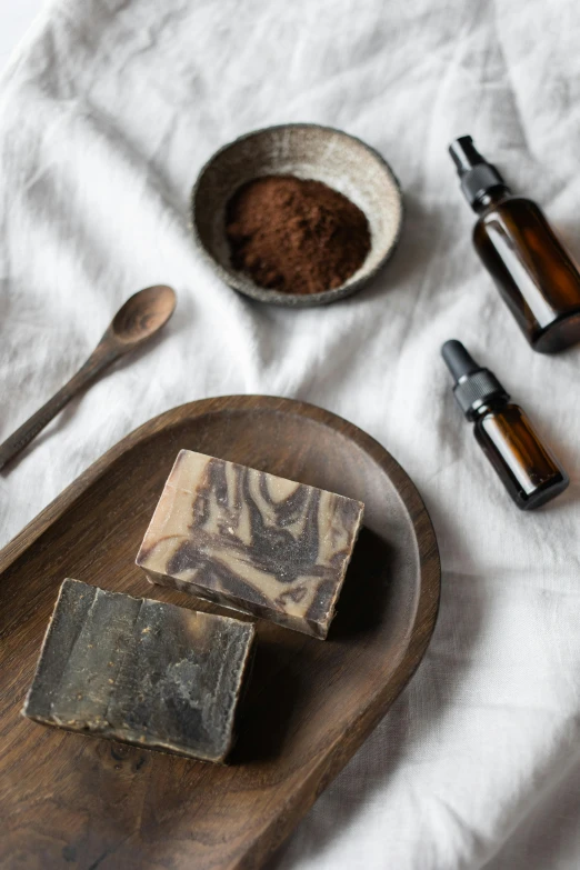 a couple of soap bars sitting on top of a wooden tray, a portrait, by Helen Stevenson, trending on unsplash, baroque, made of tar, cold brew coffee ), powder, square