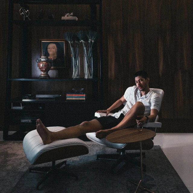 a man sitting on a chair in a living room, a portrait, pexels contest winner, maximalism, portrait of cristiano ronaldo, on a super yacht, in style of kar wai wong, f 1 driver charles leclerc