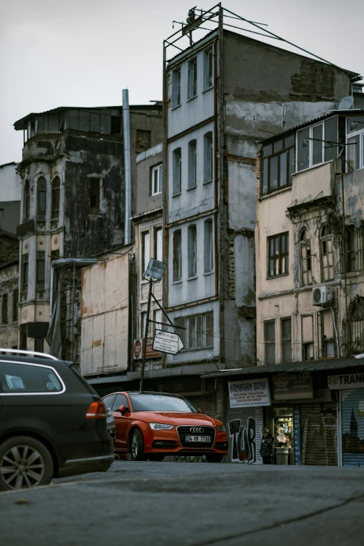 a group of cars driving down a street next to tall buildings, inspired by Elsa Bleda, renaissance, fallout style istanbul, photo of poor condition, location of a dark old house, built on a steep hill