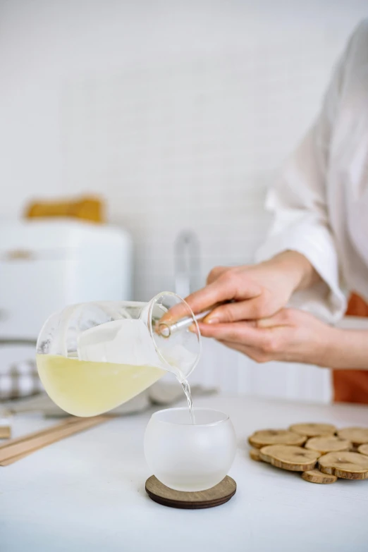 a close up of a person pouring something into a cup, inspired by Kanō Naizen, trending on pexels, renaissance, baking cookies, lemonade, white, semi-transparent