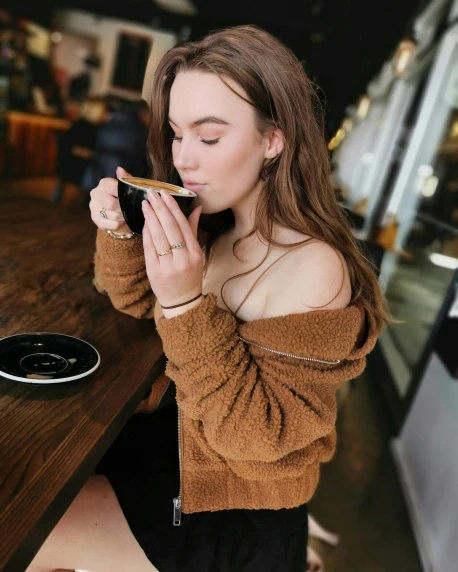 a woman sitting at a table eating a sandwich, a picture, by Robbie Trevino, trending on pexels, happening, he is wearing a brown sweater, aussie baristas, better known as amouranth, product introduction photo