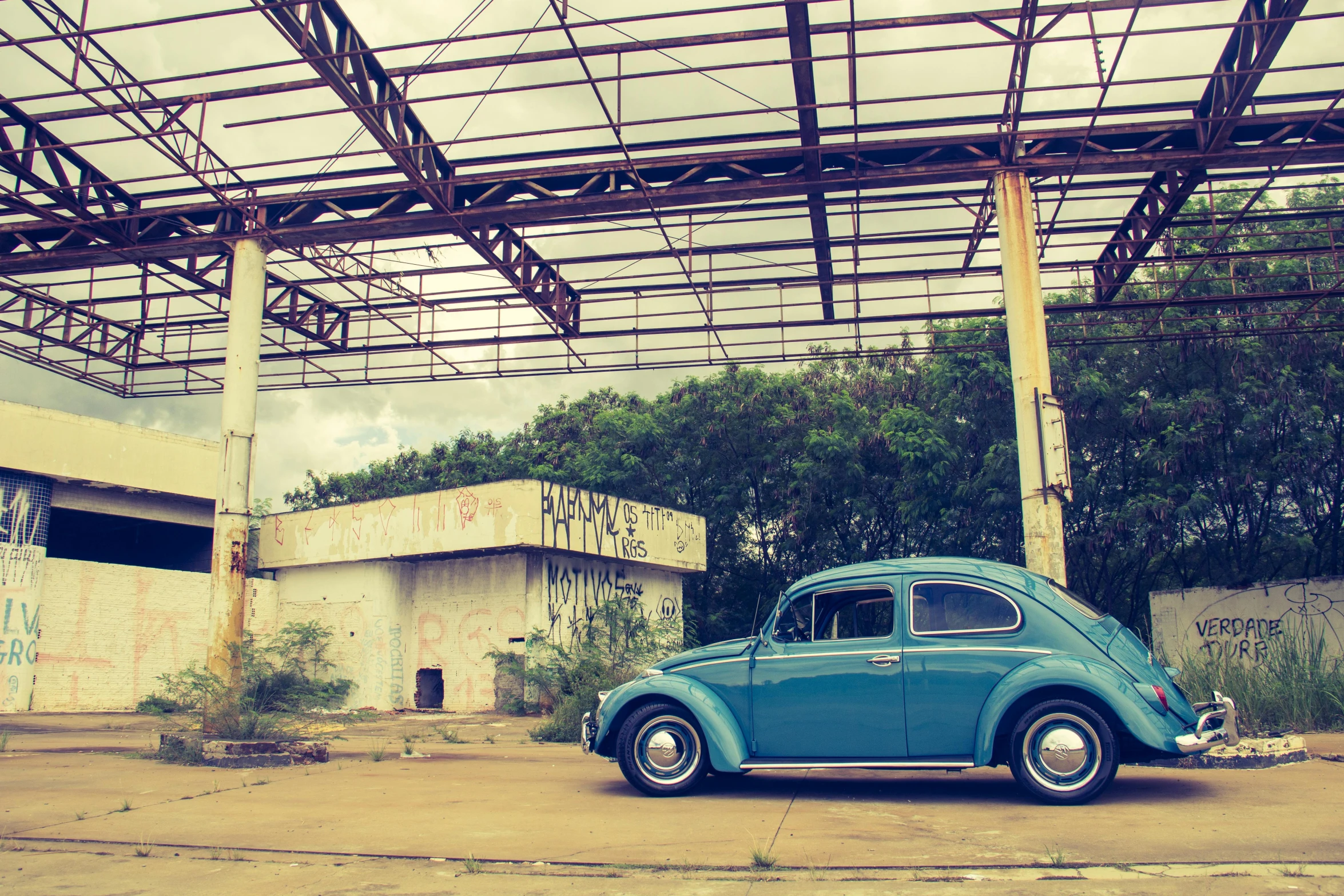 a blue car parked in front of a building, a colorized photo, by Sven Erixson, unsplash contest winner, graffiti, beetle, sepia tone, 15081959 21121991 01012000 4k, on the concrete ground