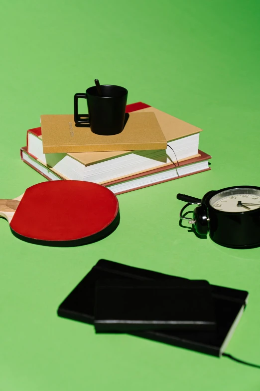 a couple of ping pong paddles sitting on top of a table, a still life, by Sven Erixson, happening, textbooks and books, breakfast, promo image, green and black color scheme