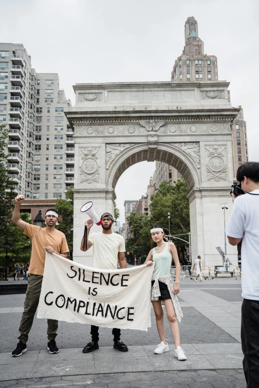 a group of people holding a sign in front of a building, by Nina Hamnett, unsplash, renaissance, jamel shabazz, silence, photo of the statue of liberty, queer