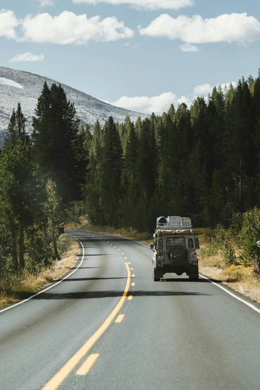 a truck driving down a road next to a forest, explorers, square, colorado mountains, scandinavian