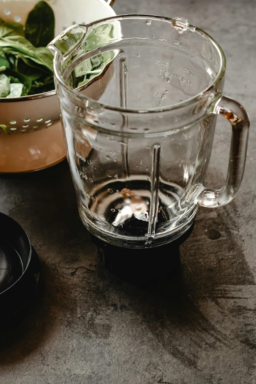a blender sitting on top of a counter next to a bowl of spinach, trending on pexels, process art, ice tea in a mason jar, moody details, brown, grey