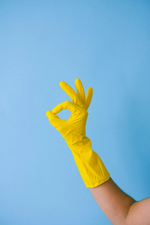 a person wearing yellow rubber gloves on a blue background, an album cover, pexels, goop, pristine clean design, peace, delightful surroundings