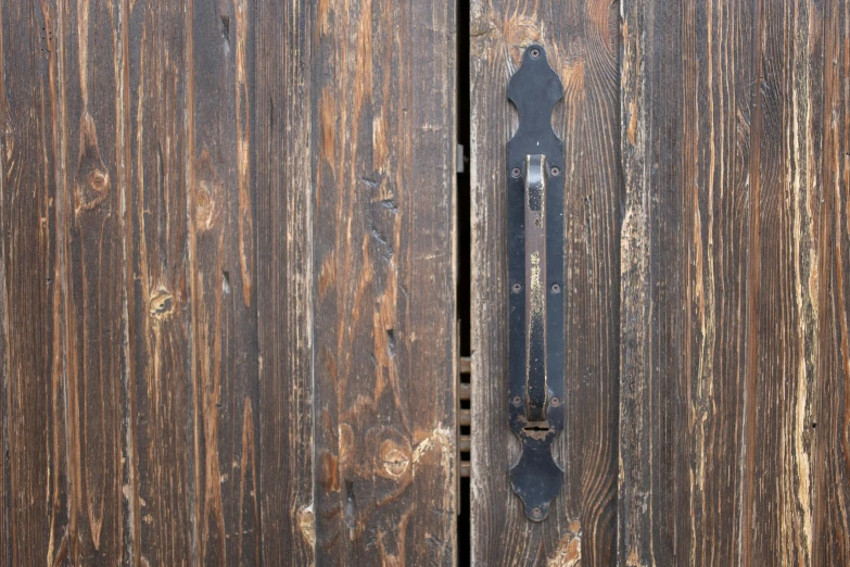 a close up of a door handle on a wooden door, by Andries Stock, unsplash, private press, black vertical slatted timber, steampunk katana, two wooden wardrobes, close up front view