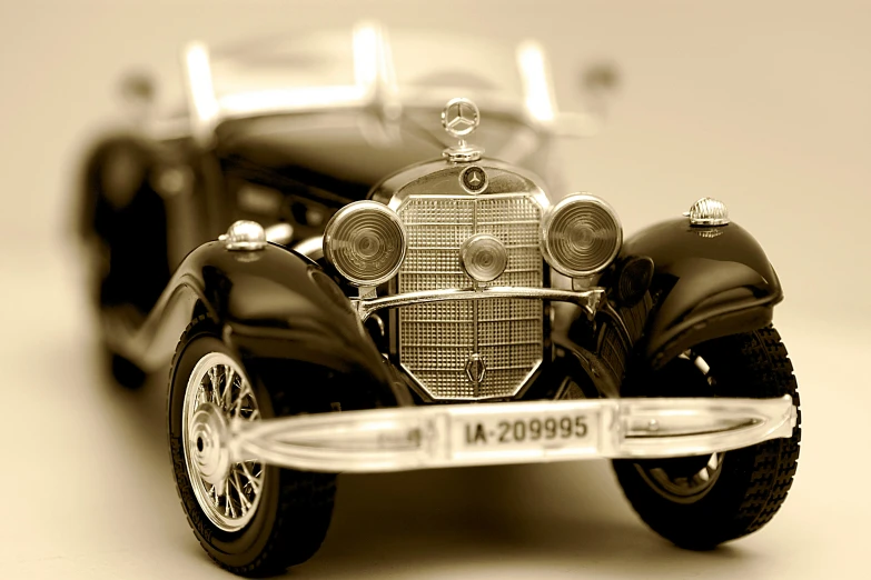 a black and white photo of a vintage car, a tilt shift photo, by David Simpson, trending on pixabay, photorealism, mercedez benz, sepia toned, toy photo, with cool headlights