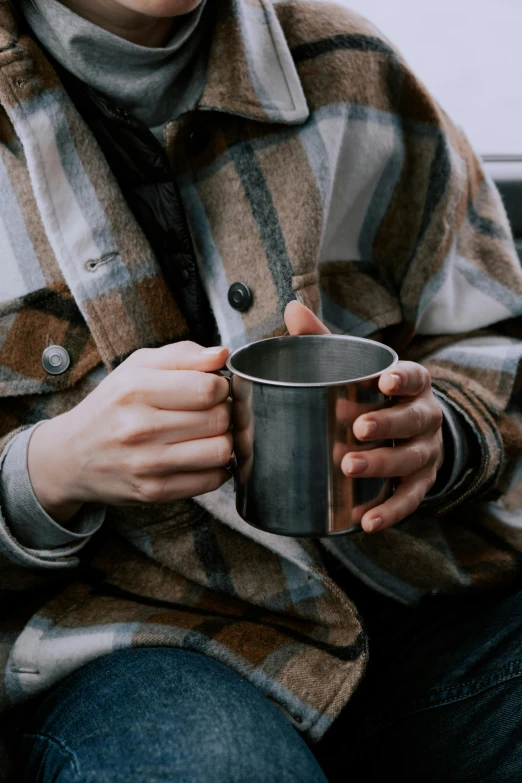 a close up of a person holding a cup, flannel, aluminum, muted browns, traveller