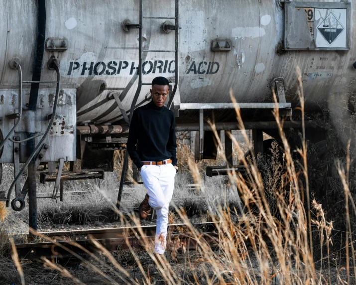 a man standing in front of a train, inspired by Michael Gustavius Payne, trending on unsplash, photorealism, acids, white and black clothing, full body shot 4k, thin young male alchemist