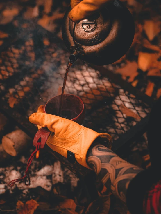 a person holding a tea pot over a fire, leather gloves, caramel. rugged, in the style of sifu 🔥 😎 🕹️ 👀 :2, spooky autumnal colours