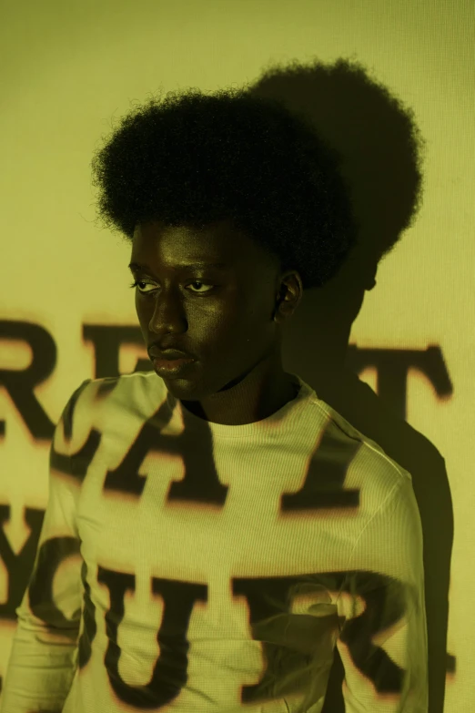 a man standing in front of a wall with graffiti on it, an album cover, inspired by Carrie Mae Weems, pexels contest winner, black arts movement, portrait androgynous girl, adut akech, with afro, light show