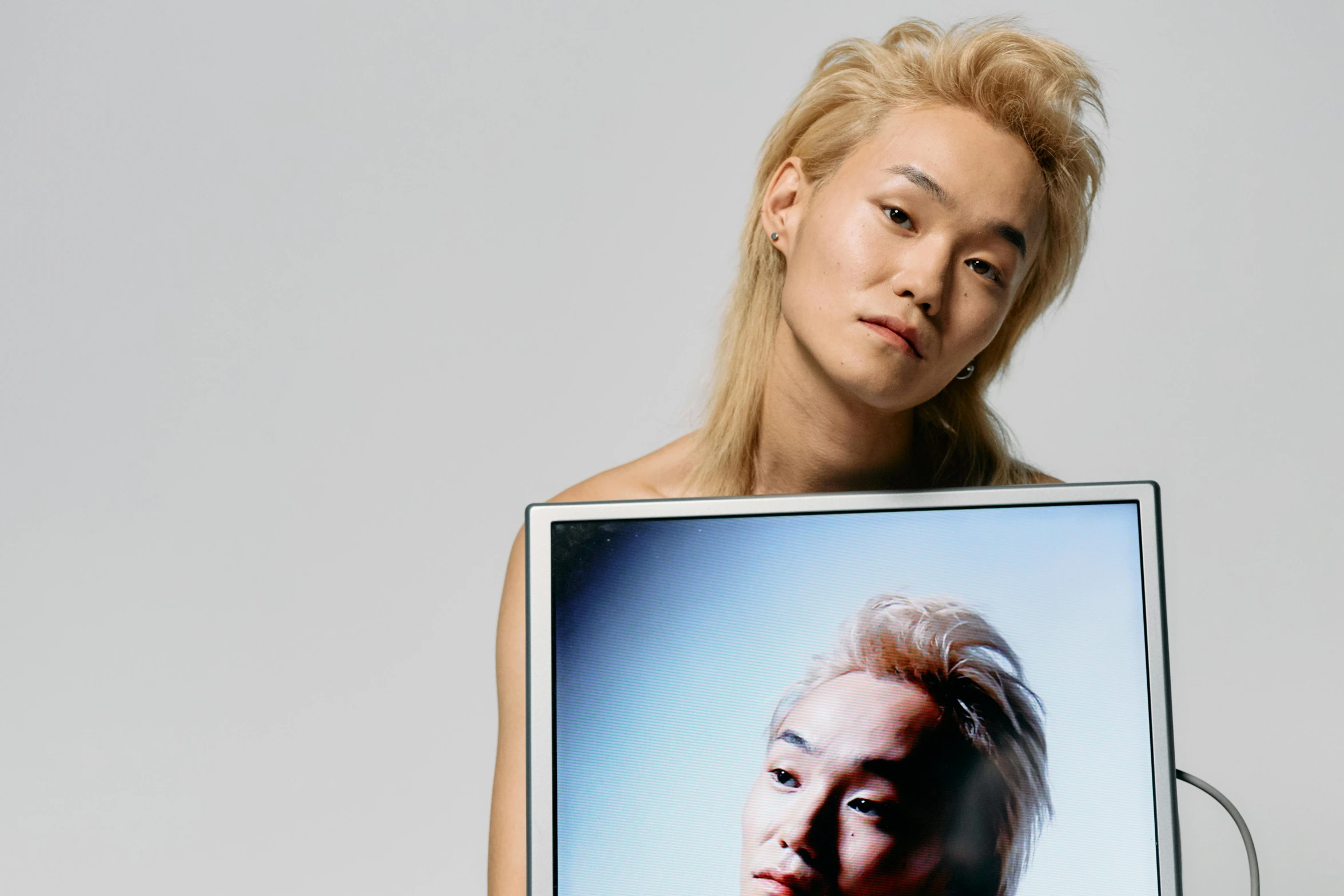 a woman holding a laptop with a picture of a woman on it, an album cover, inspired by Russell Dongjun Lu, long swept back blond hair, asian man, billboard image, hong june hyung