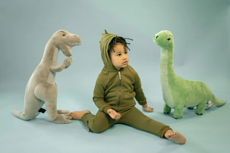 a baby sitting in front of three stuffed dinosaurs, inspired by Adam Rex, tracksuit, olive green, medium - shot, panels