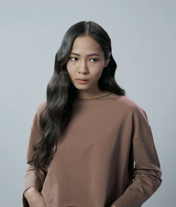 a woman standing with her hands in her pockets, an album cover, inspired by Kim Tschang Yeul, trending on pexels, hyperrealism, he is wearing a brown sweater, headshot photograph, wavy, faridah malik