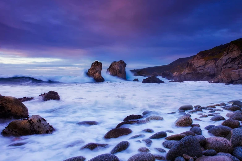 a large body of water with rocks in the foreground, unsplash contest winner, romanticism, purple omnious sky, roaring ocean in front, new zealand, rock arches