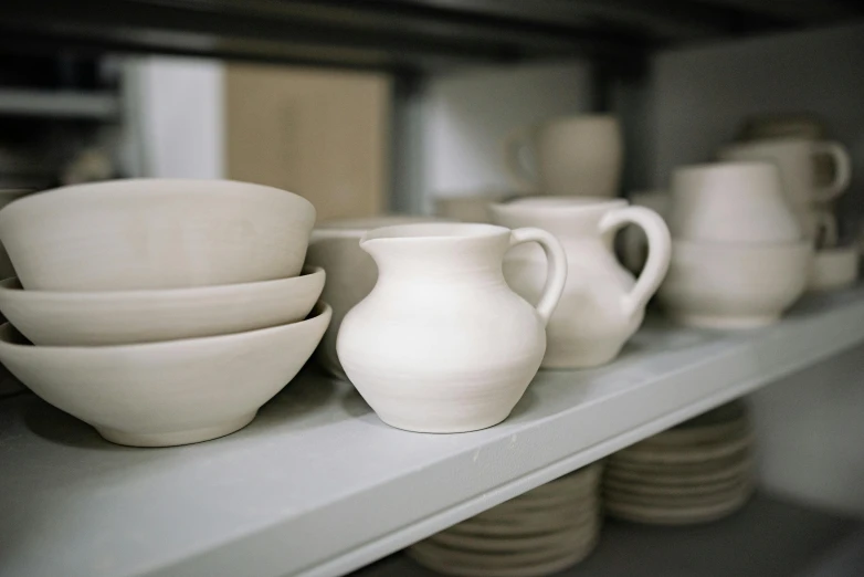 a number of bowls and cups on a shelf, a still life, inspired by Lewis Henry Meakin, unsplash, in a workshop, off-white plated armor, introduction factory photo, unfinished