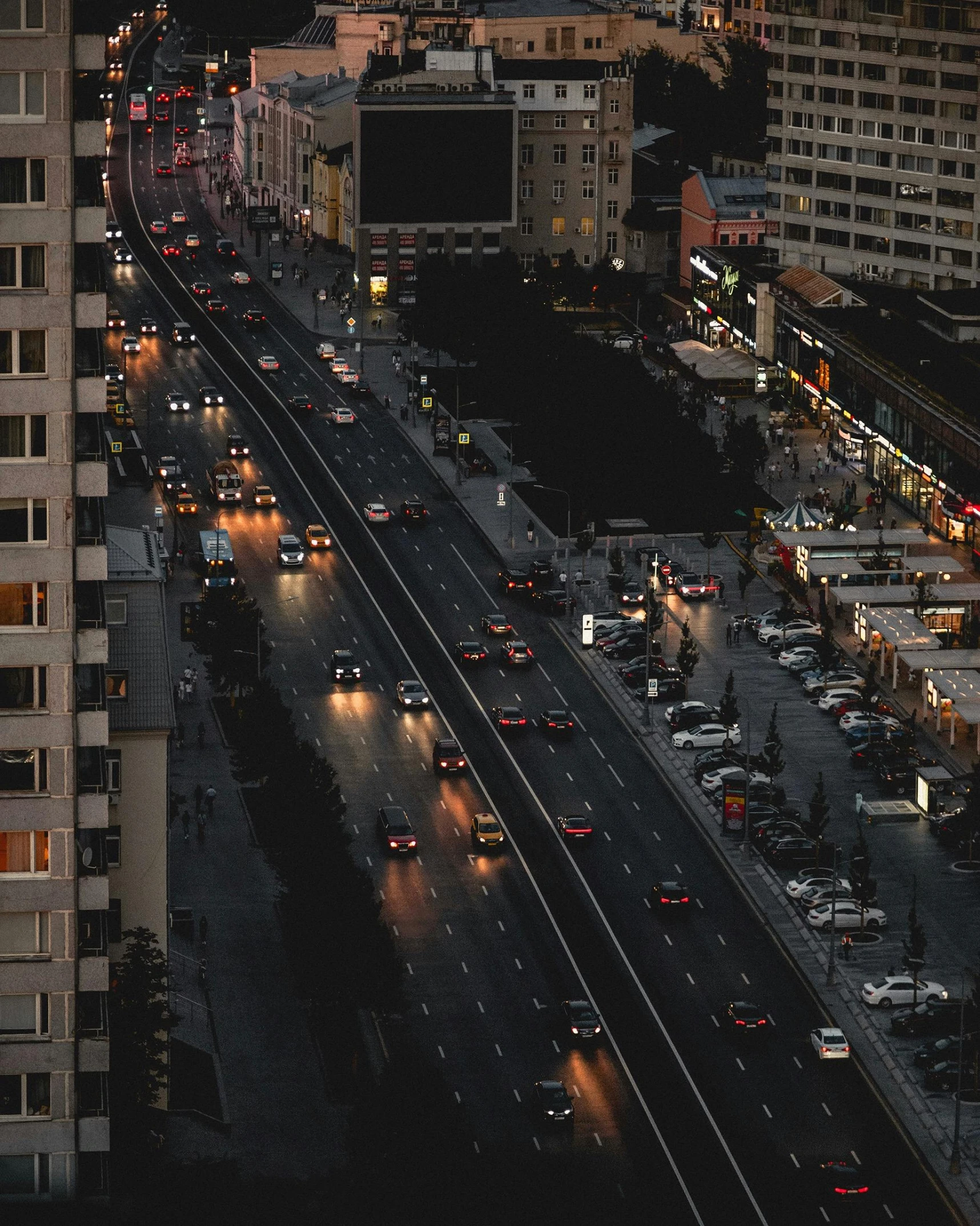 a city street filled with lots of traffic next to tall buildings, by Adam Rex, unsplash contest winner, hyperrealism, dark wet road, russian city, instagram story, high - angle view