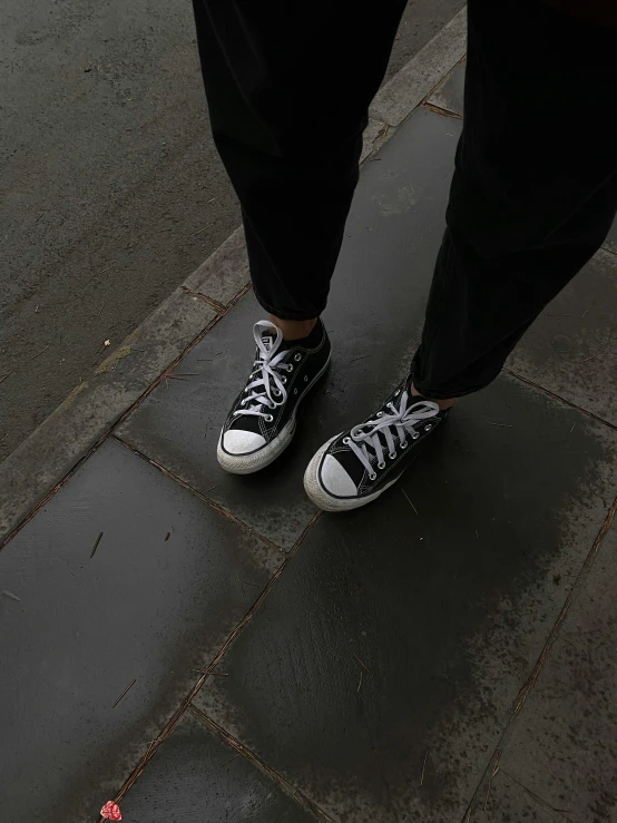 a person standing on a sidewalk holding an umbrella, wearing white sneakers, (aesthetics), profile image, black and grey