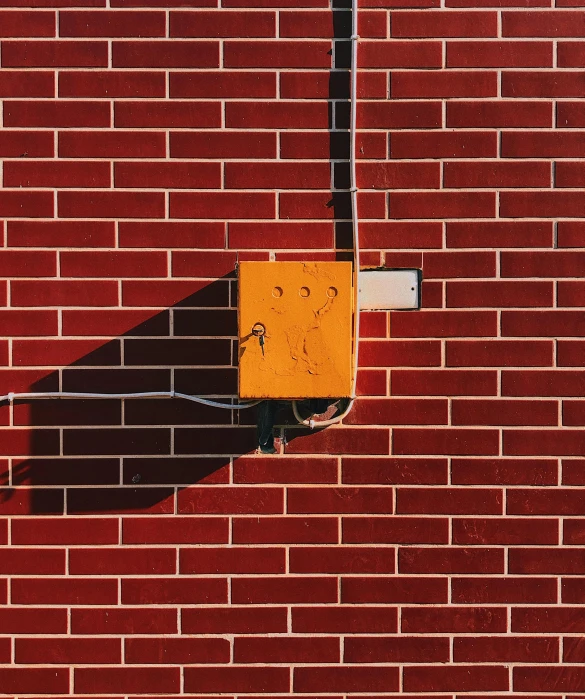 a fire hydrant on the side of a brick building, an album cover, by Attila Meszlenyi, pexels contest winner, postminimalism, electrical wiring!, perfect shadow, yellow-orange, 15081959 21121991 01012000 4k