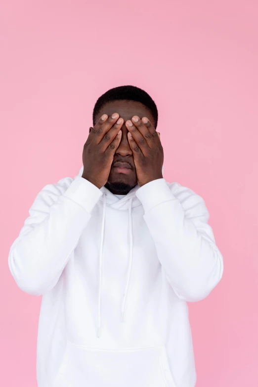 a man in a white hoodie covers his eyes with his hands, by Cosmo Alexander, trending on pexels, ((pink)), kevin hart, thicc, stripe over eye