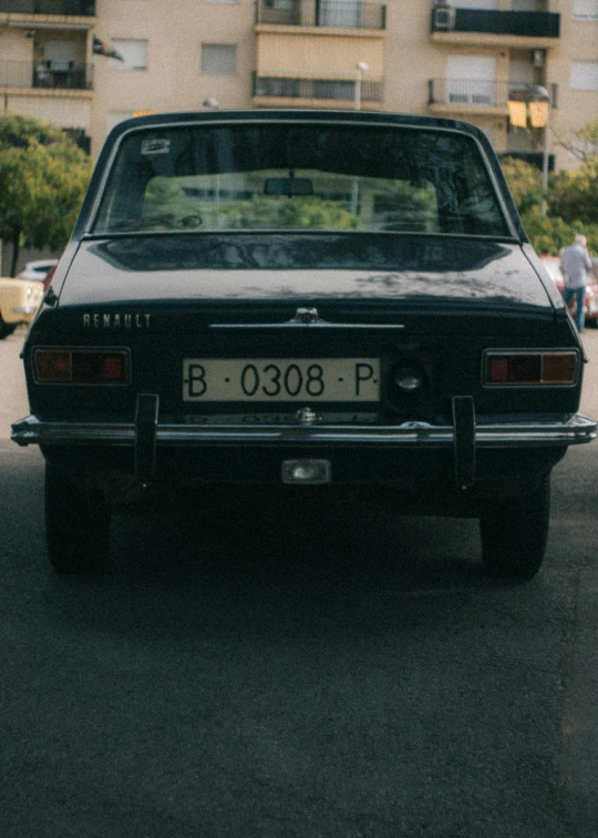 a black car parked in front of a tall building, an album cover, by Elsa Bleda, pexels contest winner, renaissance, 1 9 7 0 s car window closeup, damascus, renault ultimo, rear view
