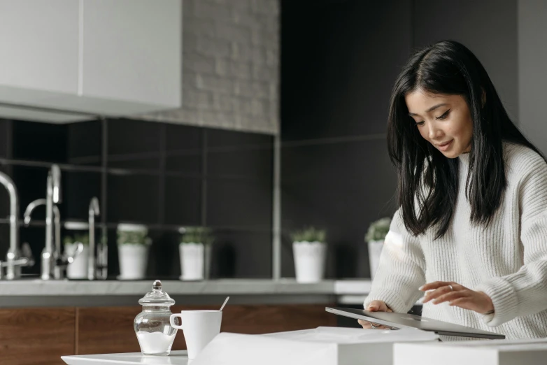a woman sitting at a kitchen counter using a tablet, trending on pexels, asian female, background image, standing on a desk, professional image